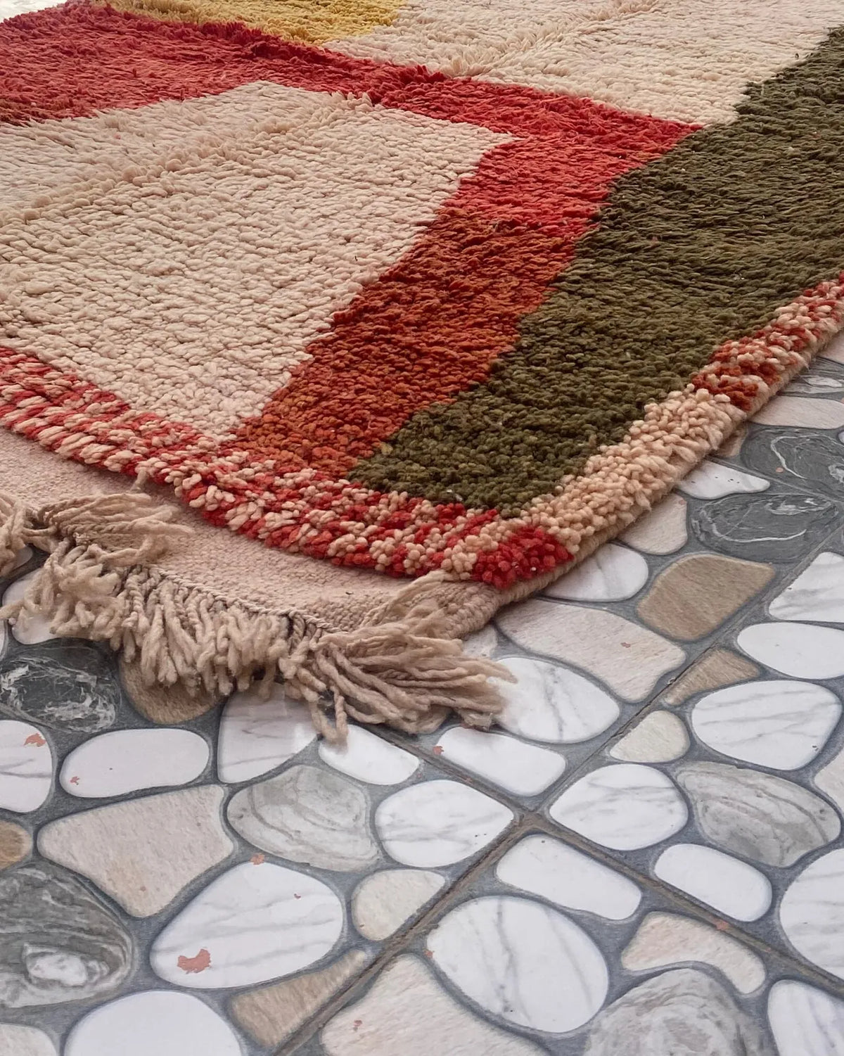 Red and Olive Color Block Moroccan Rug, seen at an angle on the workshop floor