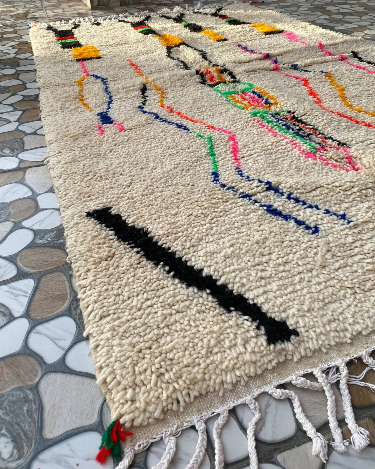 Ivory Line Art Azilal Rug, seen at an angle on the workshop floor