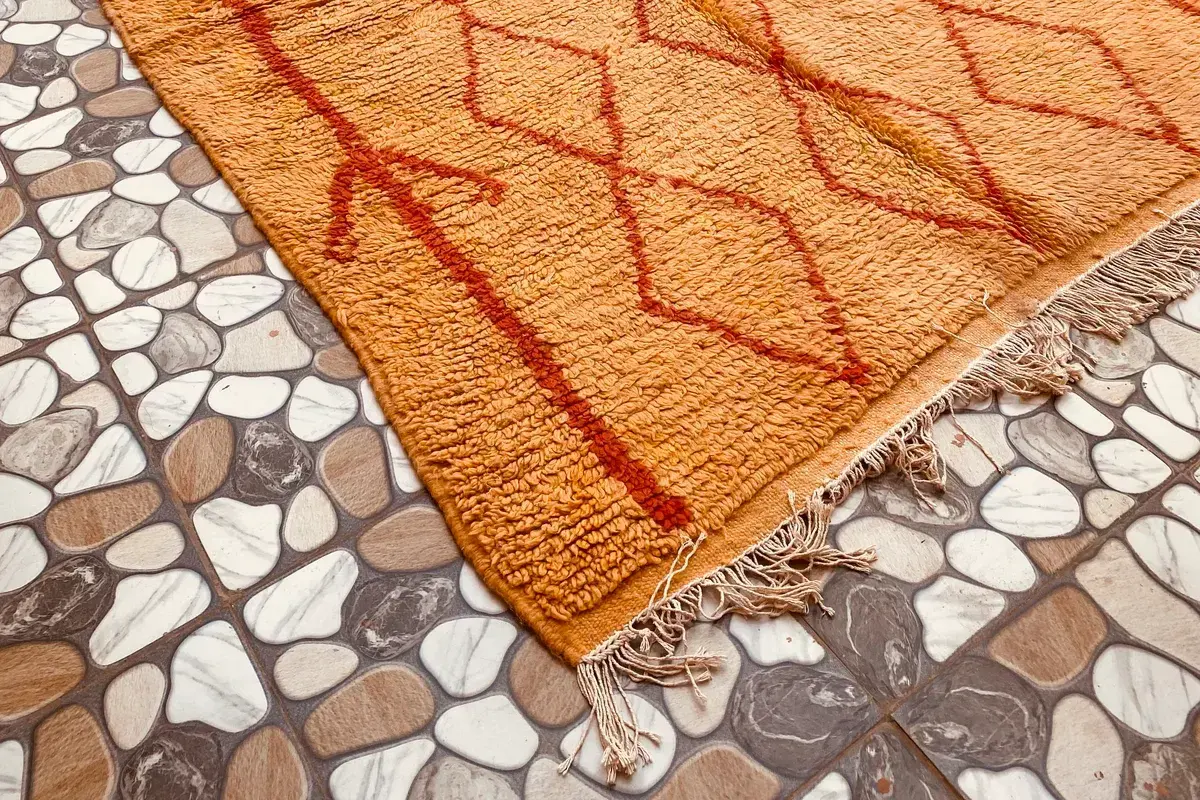 Mustard yellow Moroccan rug with rust-red diamonds on a tiled floor