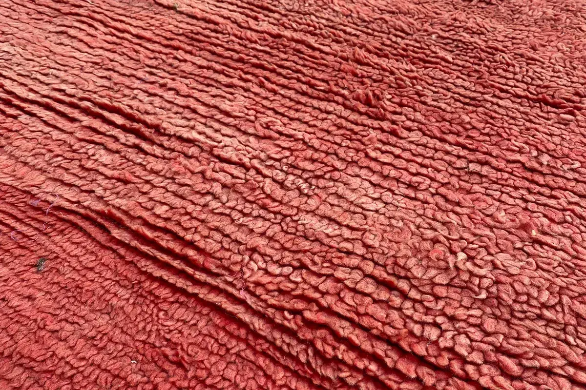 Close-up of the thick rust-red wool pile of a hand-knotted rug