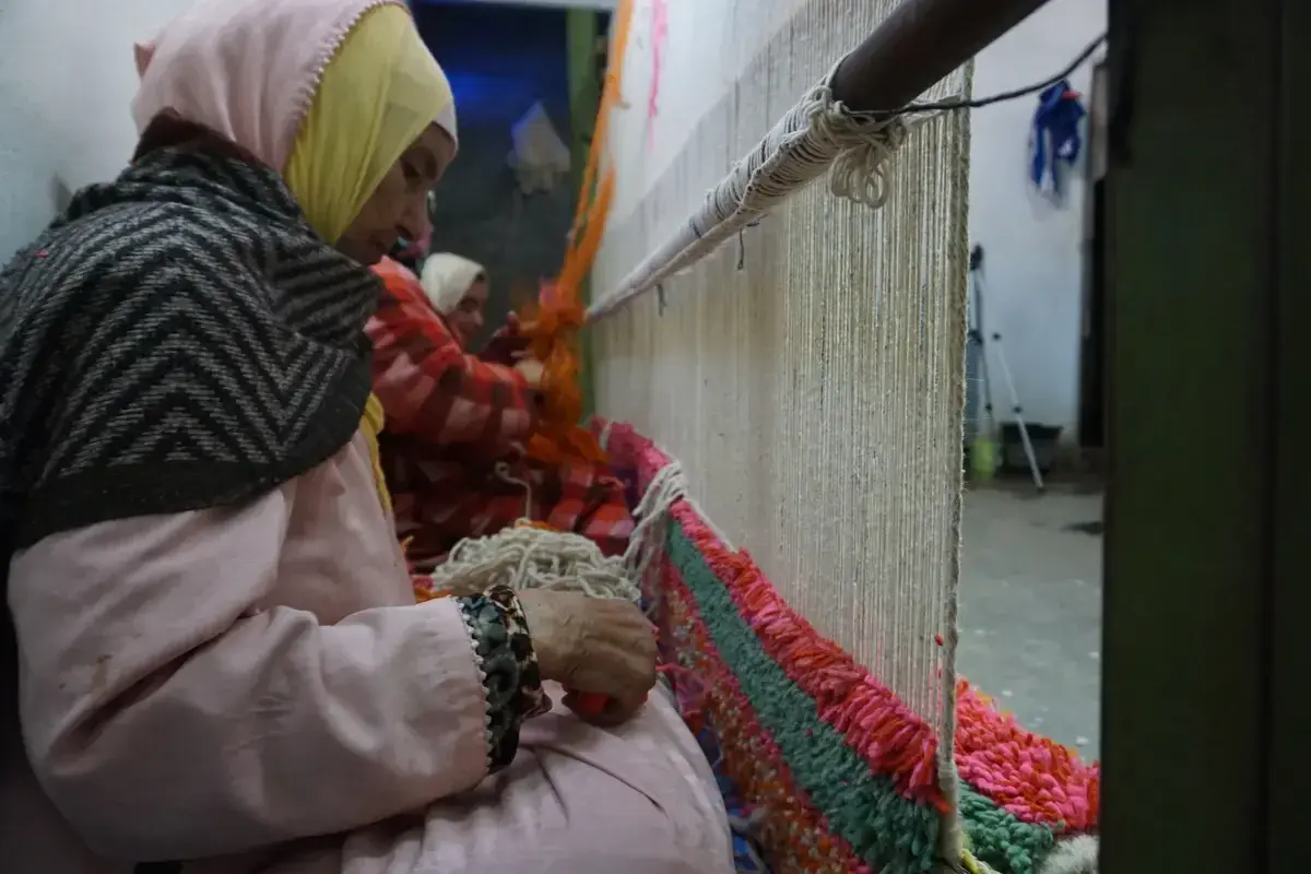 Close-up of an artisan's hands knotting wool onto a loom