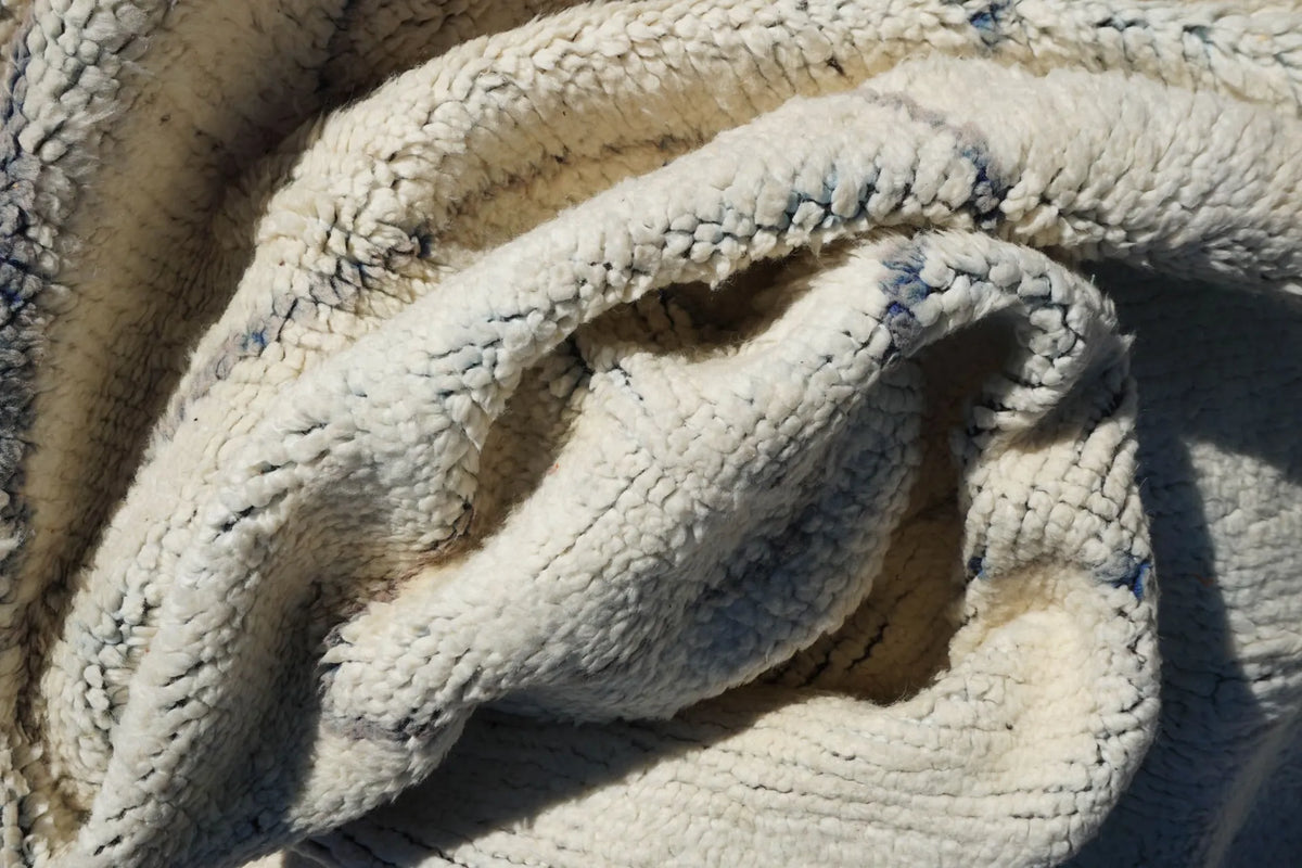 Close-up of the hand-knotted wool pile of a cream Moroccan rug