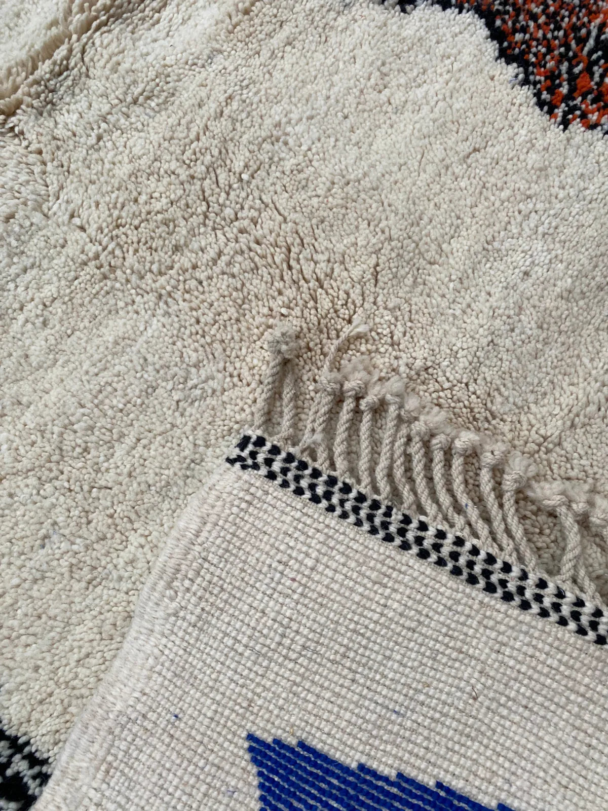 A corner of a hand-knotted ZenRug turned over to show the woven edge and the knots on the back