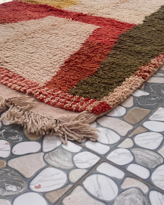 Red and Olive Color Block Moroccan Rug, seen at an angle on the workshop floor