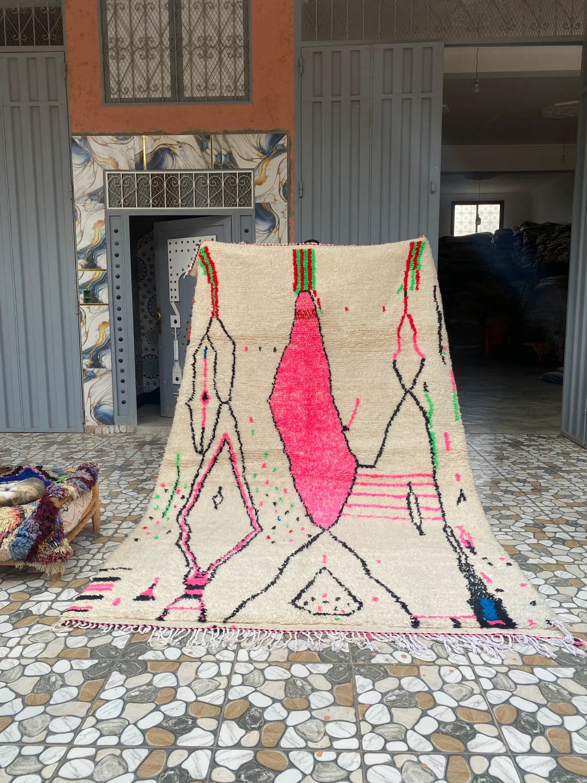 Hot Pink and Ivory Azilal Rug, the whole rug held up in front of the workshop