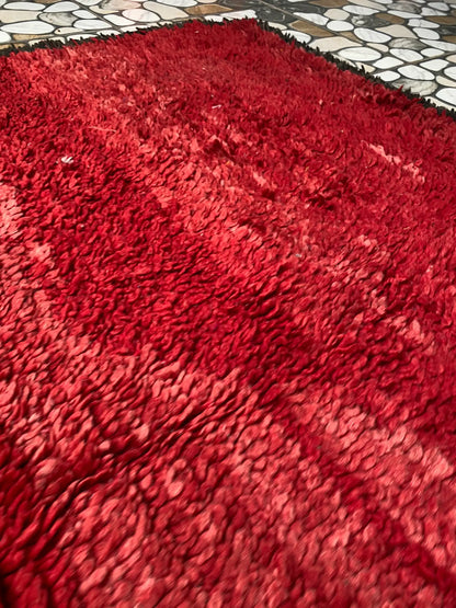 Angled close-up of the plush red pile with soft pink and deep crimson shading, with tiled floor at the top edge